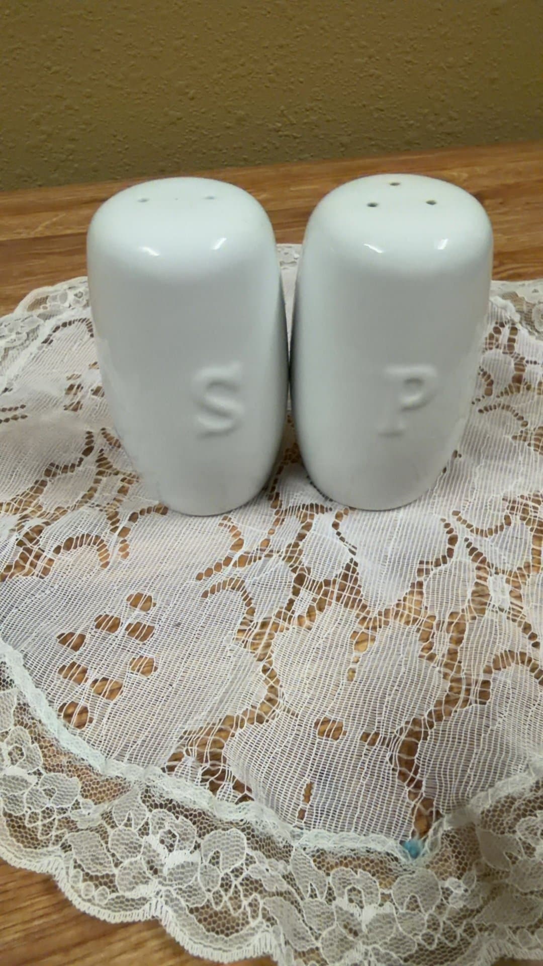 White Ceramic Salt and Pepper Shakers on Lace Doily - Image 1